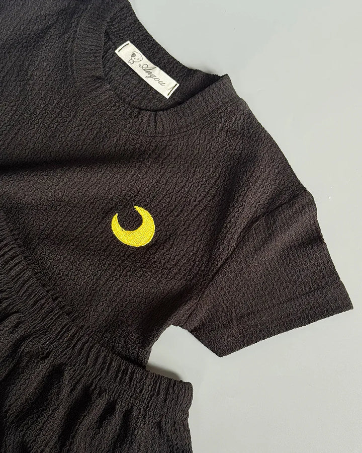 Black baby romper with yellow crescent moon design on a light gray background