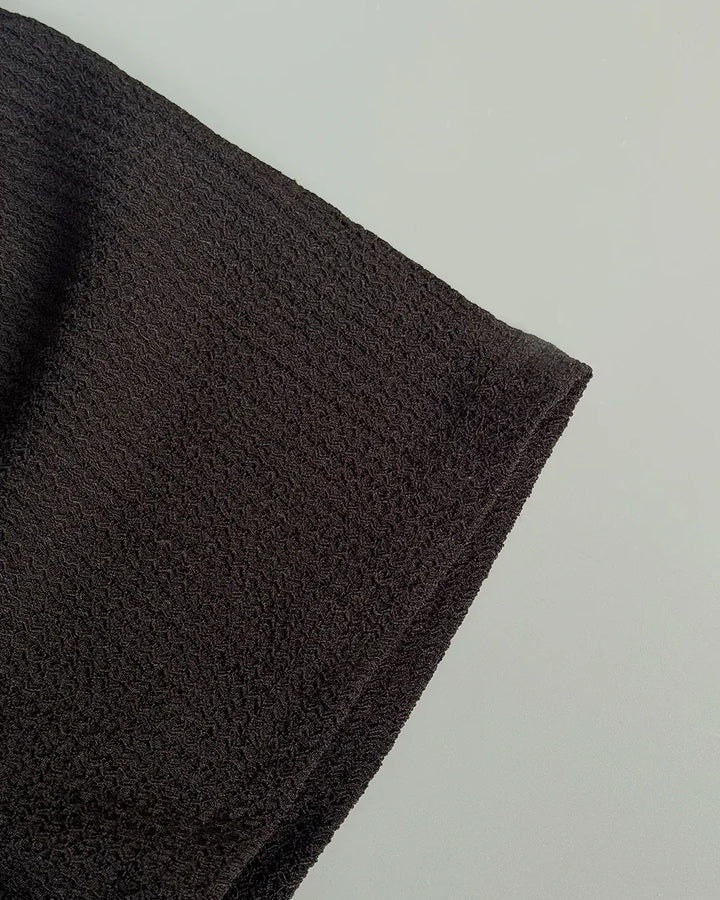 Close-up of a dark brown fabric texture on a light gray background