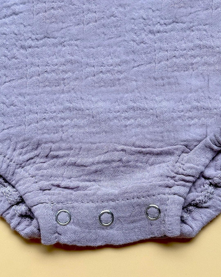 Close-up of a textured purple fabric with metal grommets on a beige background