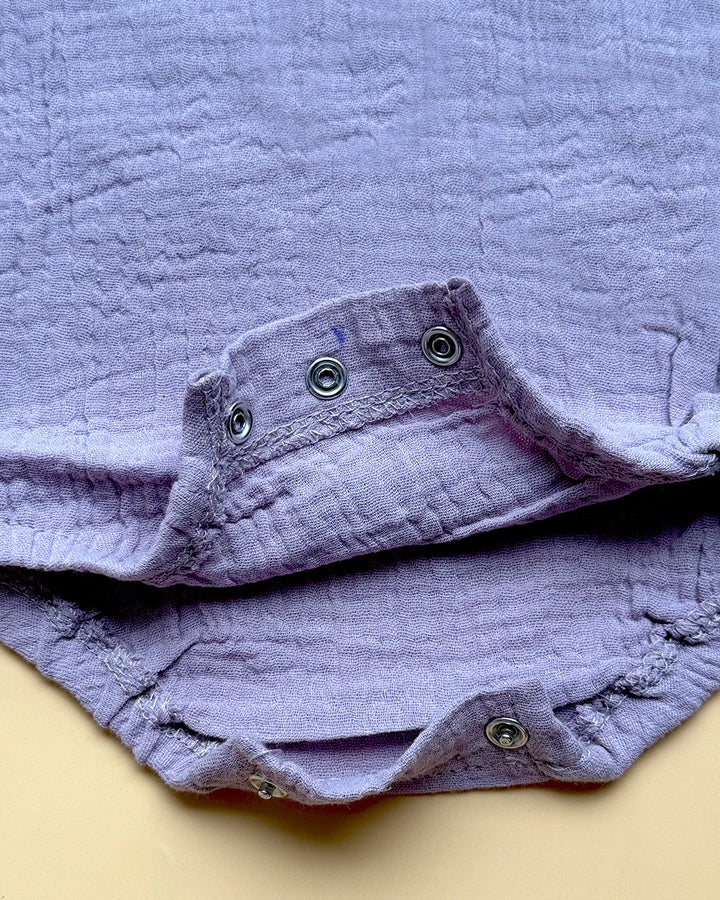 Folded purple fabric with button details on a beige background