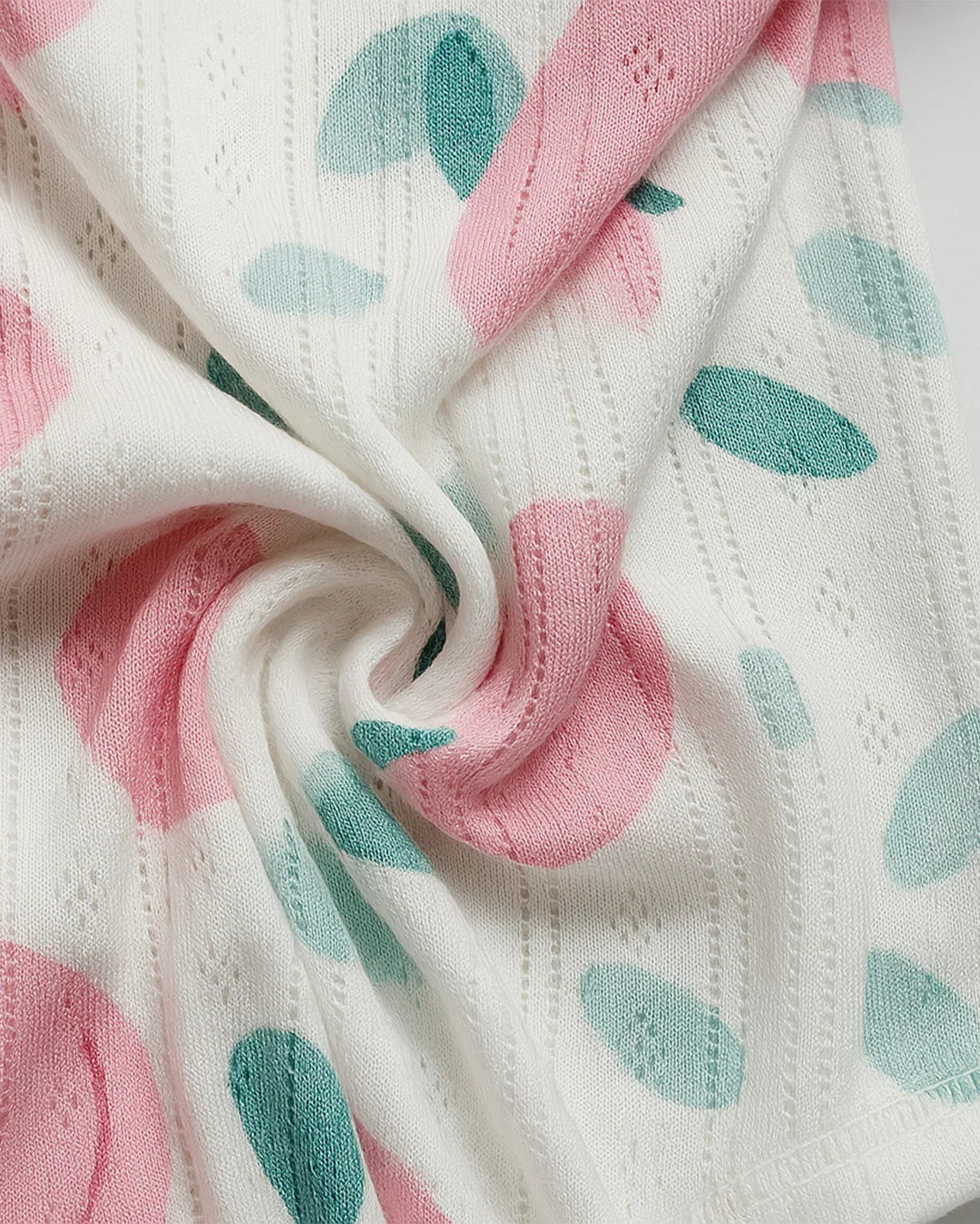 Close-up of a fabric with pink and green leaf patterns on a white background