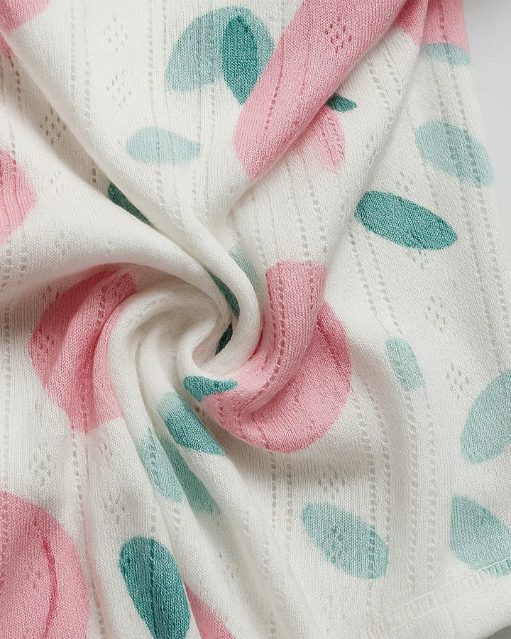 Close-up of a fabric with pink and green leaf patterns on a white background