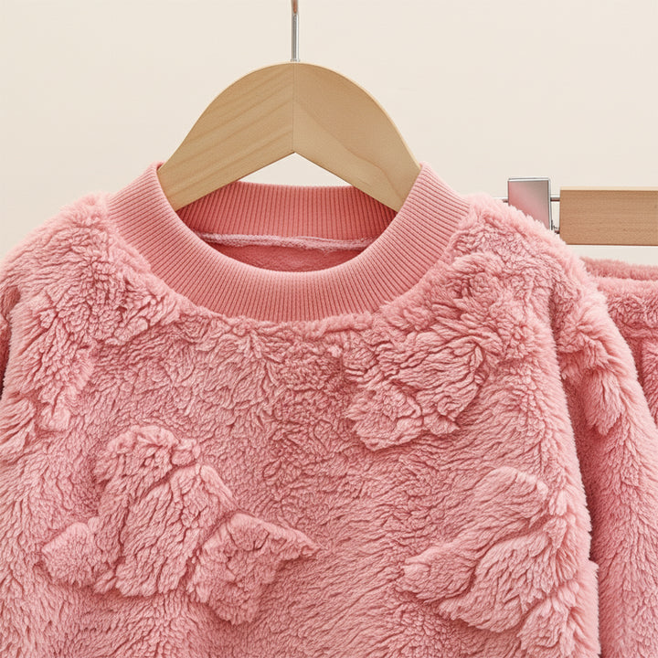 Pink textured sweater on a wooden hanger against a neutral background