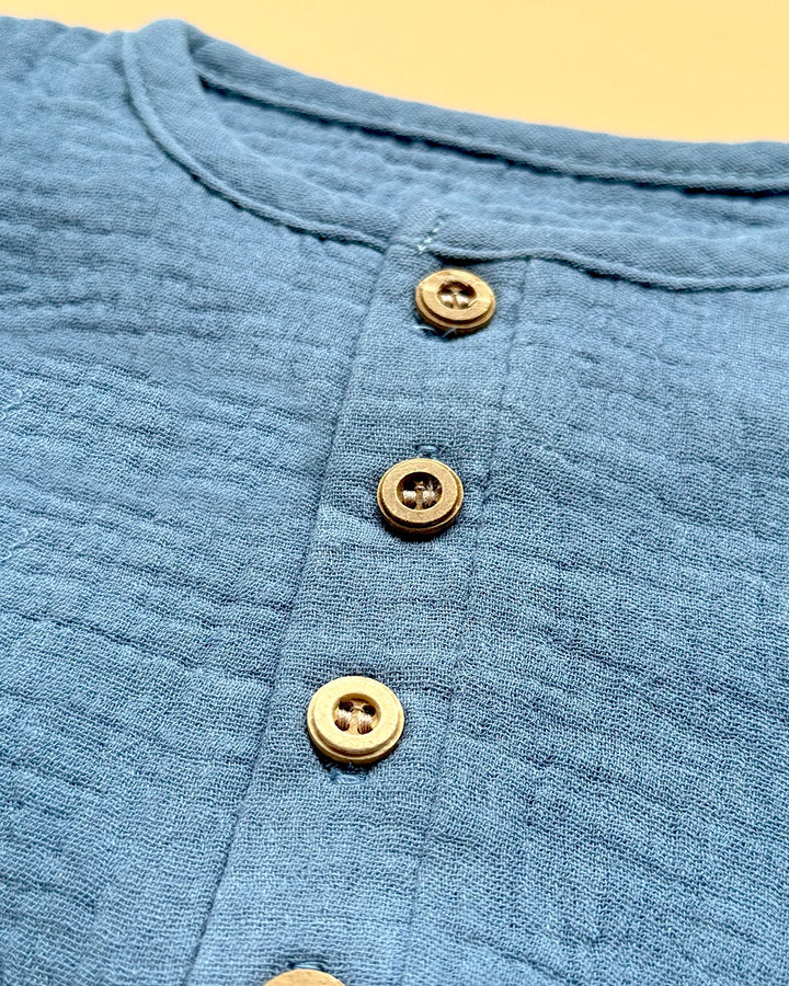 Close-up of a blue textured fabric with gold buttons on a yellow background