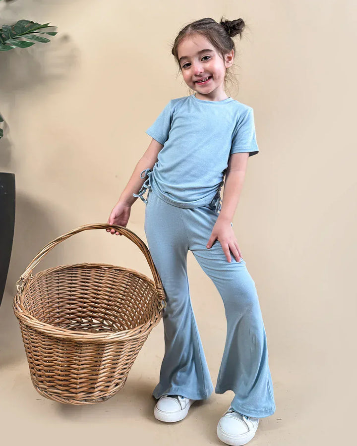 Child in light blue outfit holding a wicker basket against a beige background