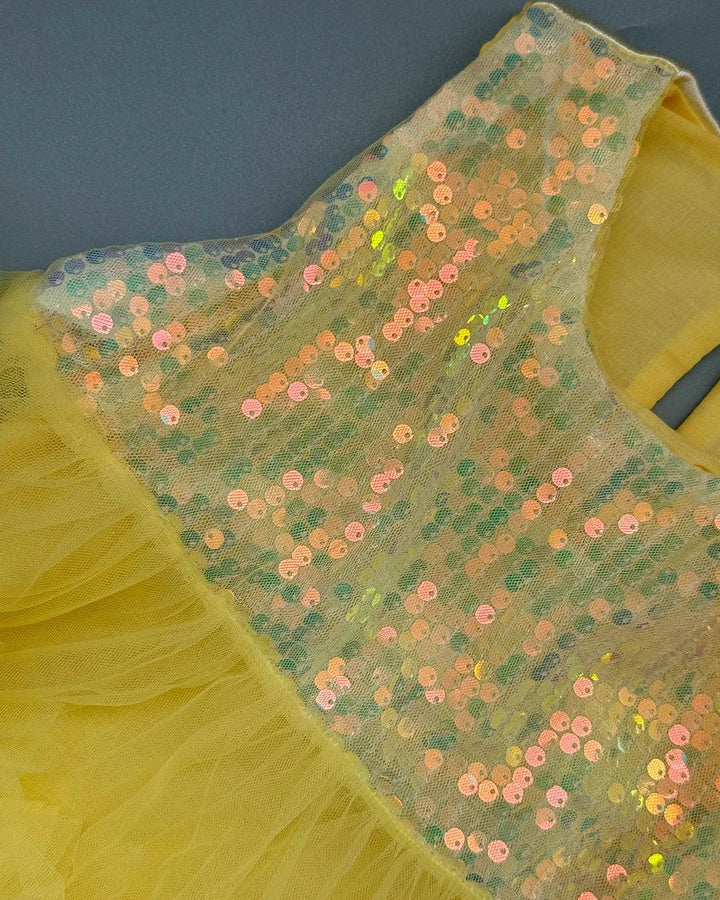 Yellow dress with sequin embellishments on a dark background