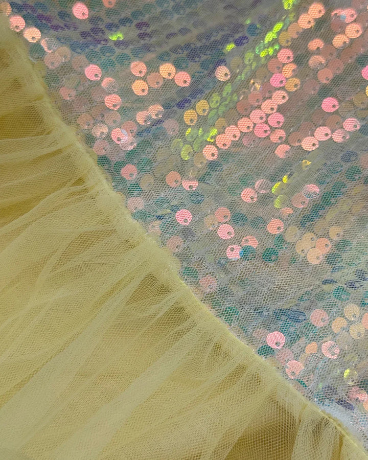 Close-up of yellow fabric with a textured pattern next to a sheer fabric with colorful sequins.