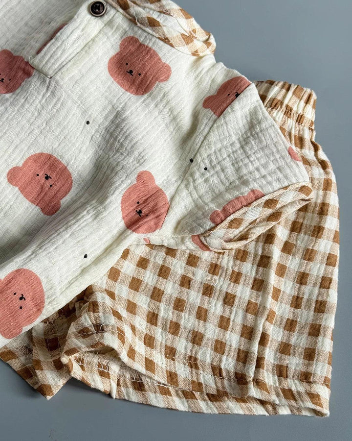 Folded fabric with pink bear patterns and brown checkered pattern on a gray background