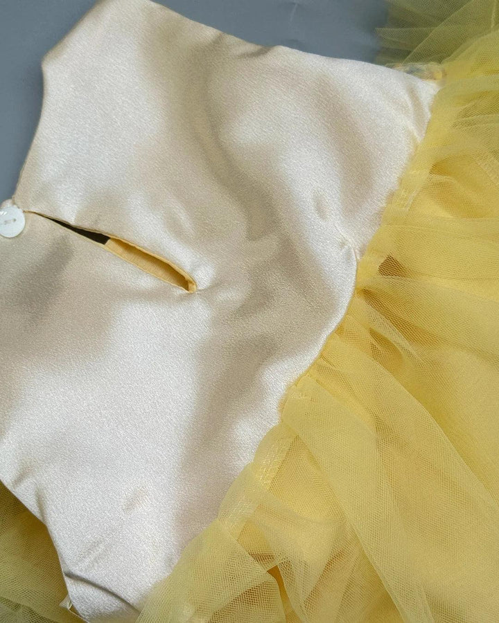 Close-up of a yellow and white dress with a button detail.