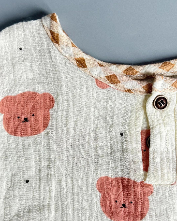 Close-up of a baby outfit with bear face patterns on a neutral background