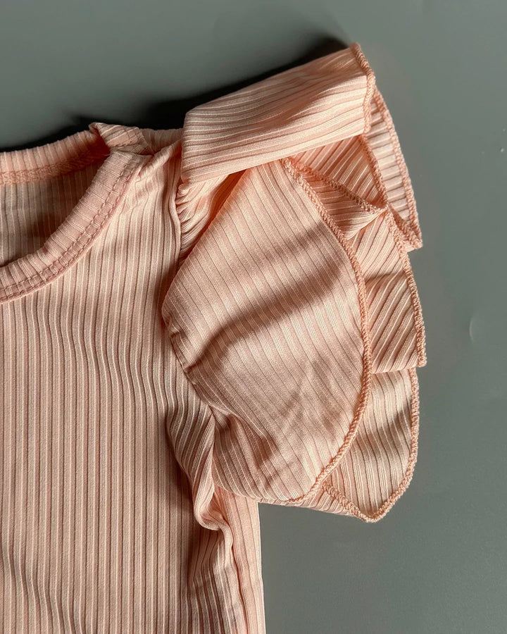 Close-up of a ribbed pink garment with ruffled details on a gray background