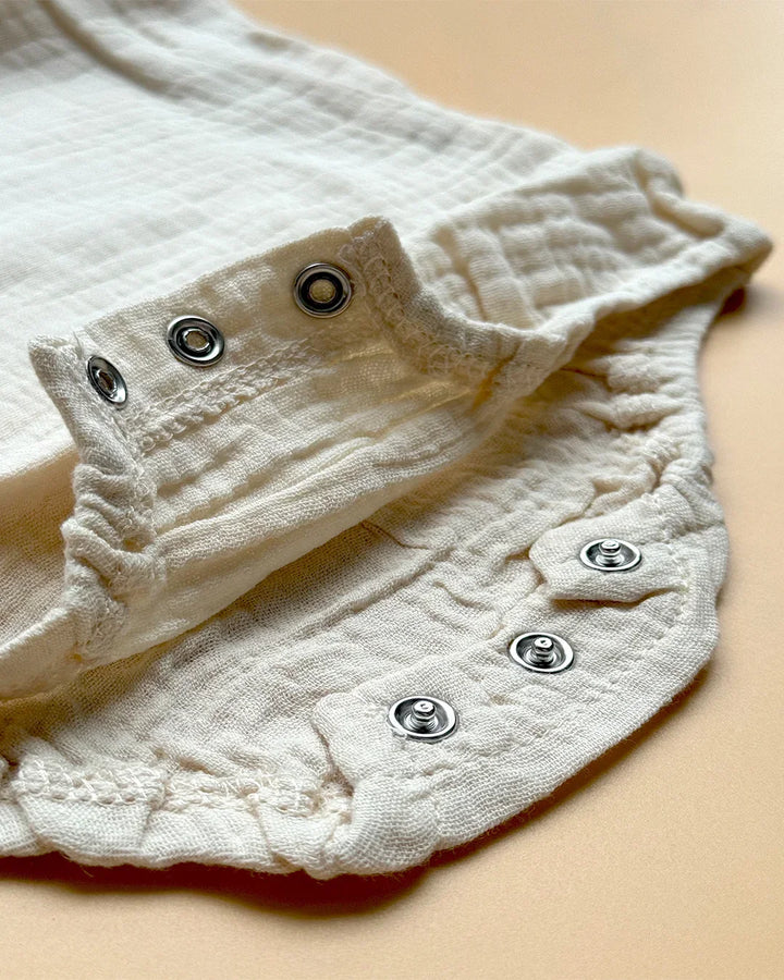 Close-up of a white textured garment with buttons on a beige background