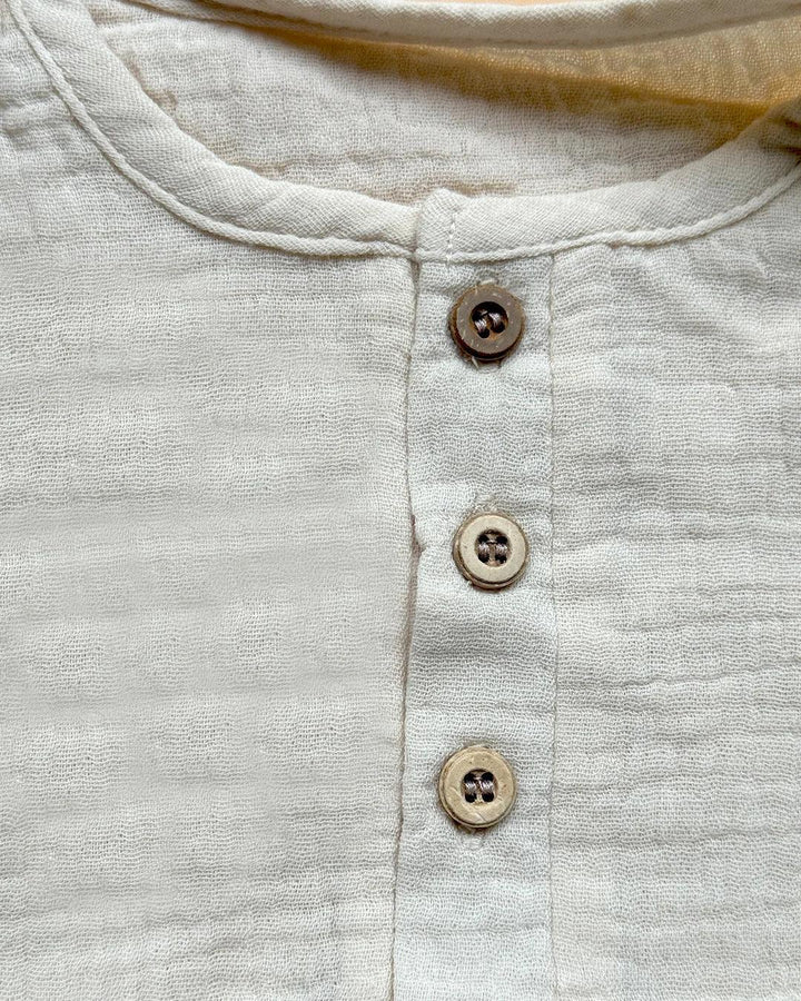 Close-up of a light gray shirt with brown buttons