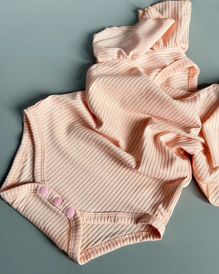 Pink ribbed baby romper on a gray background