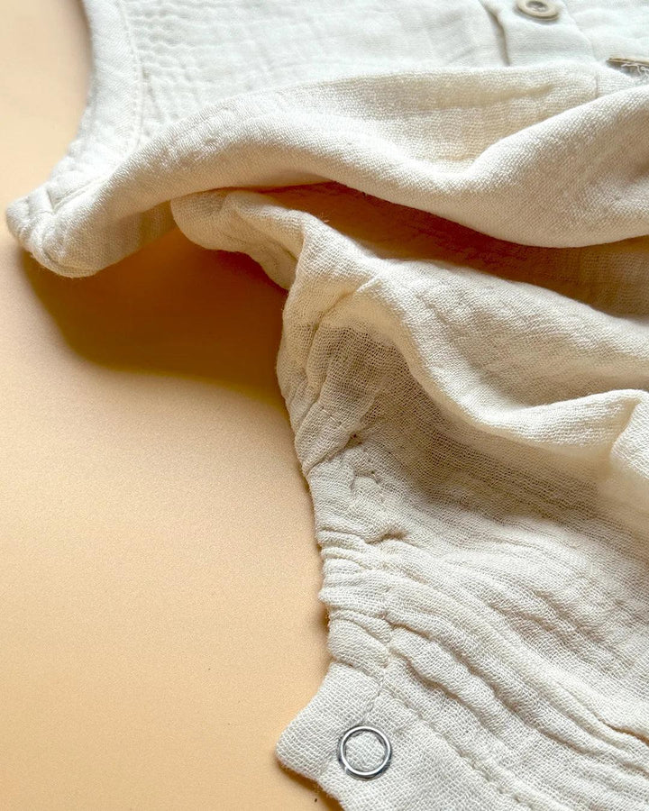 Close-up of a white baby romper on a beige surface