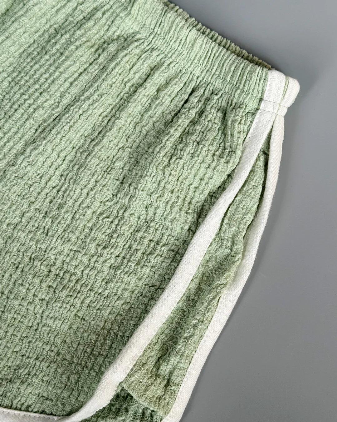 Green textured fabric with white trim on a gray background
