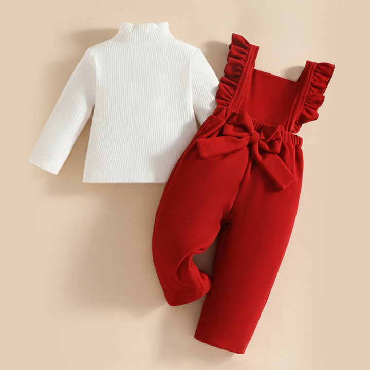 White long-sleeve top and red ruffled overalls on a beige background