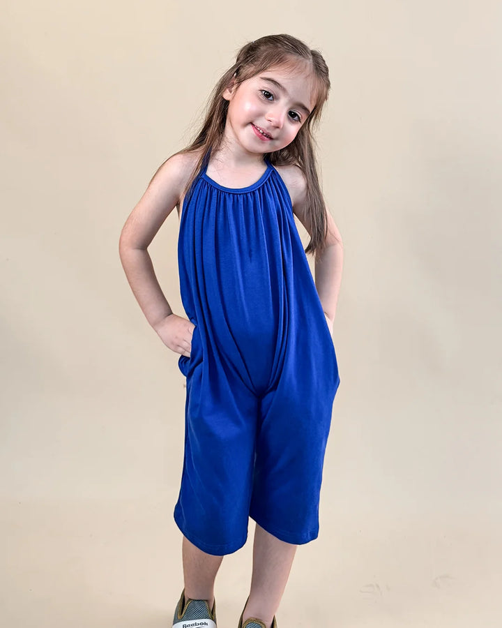 Young girl wearing a blue sleeveless dress with a plain background