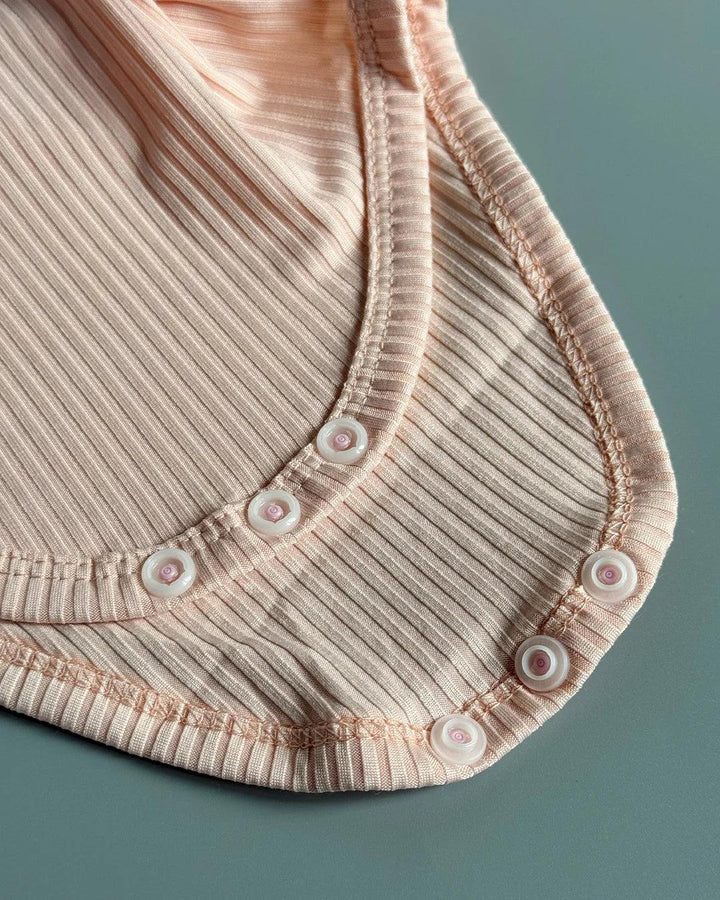 Close-up of a ribbed pink garment with button details on a teal background
