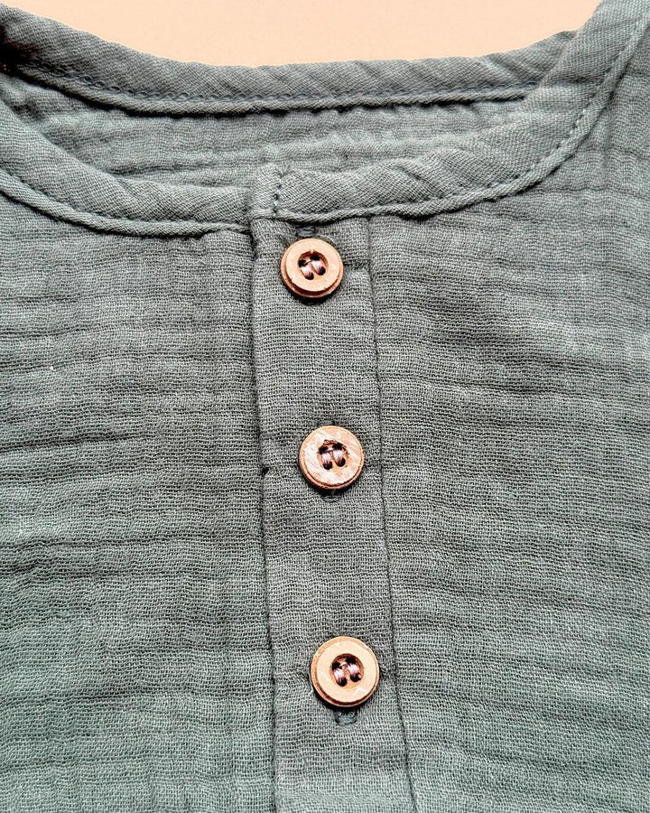 Close-up of a green garment with button details on a beige background