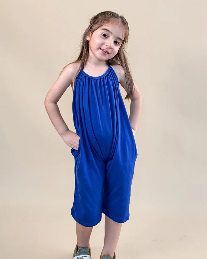 Young girl wearing a blue dress against a beige background