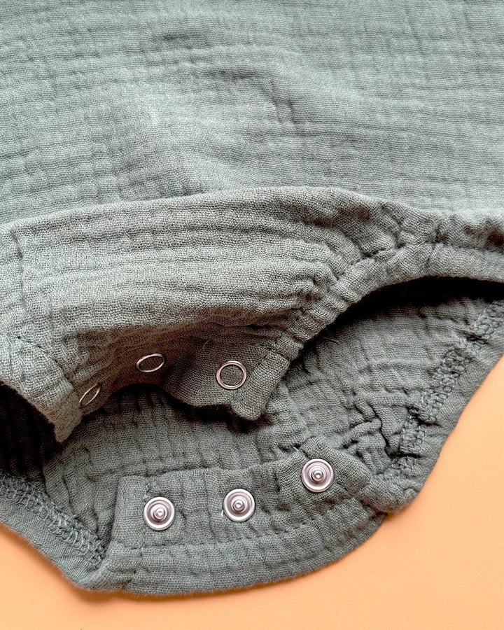 Close-up of a textured gray garment with buttons on a beige background