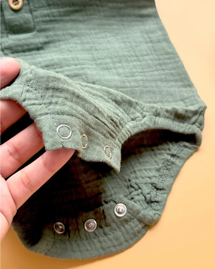 Close-up of green fabric with metal buttons on a beige background