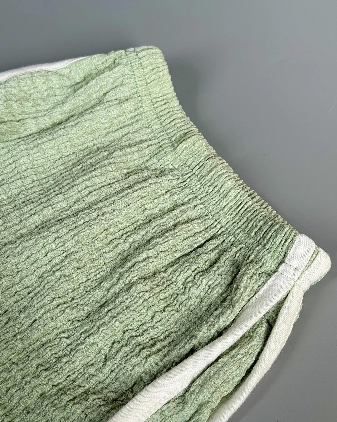 Green textured fabric with white trim on a gray background