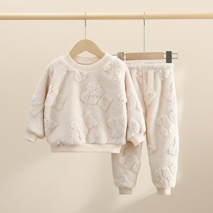White textured sweater and pants set on a hanger against a beige background