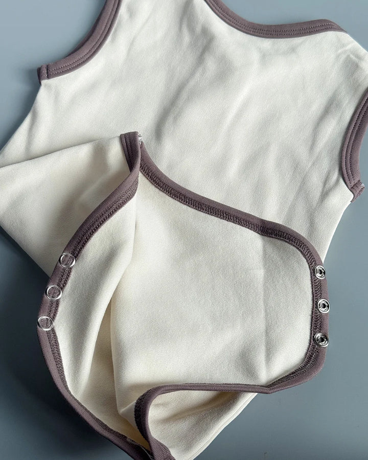 White baby bodysuit with brown trim on a gray background
