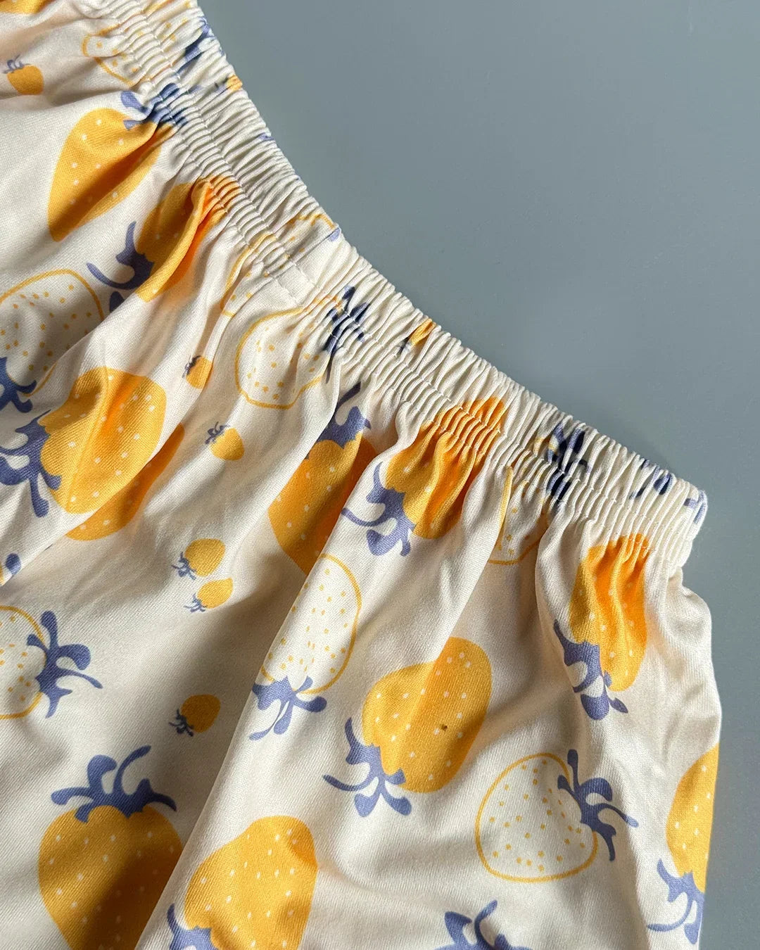 Close-up of a garment with yellow and blue pattern on a gray background