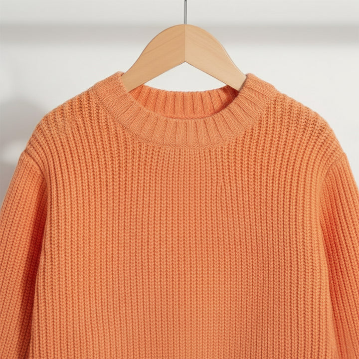 Orange sweater on a wooden hanger against a plain background