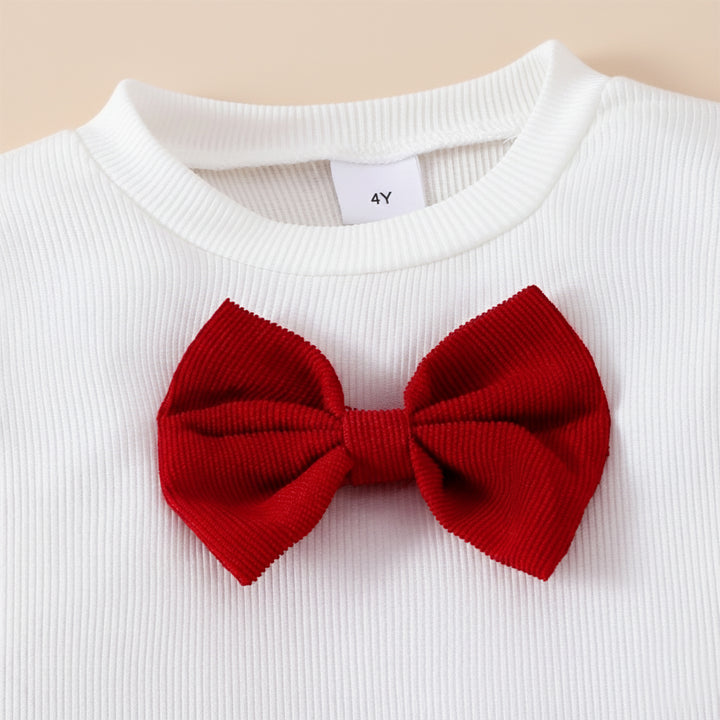 White sweater with a large red bow on a beige background