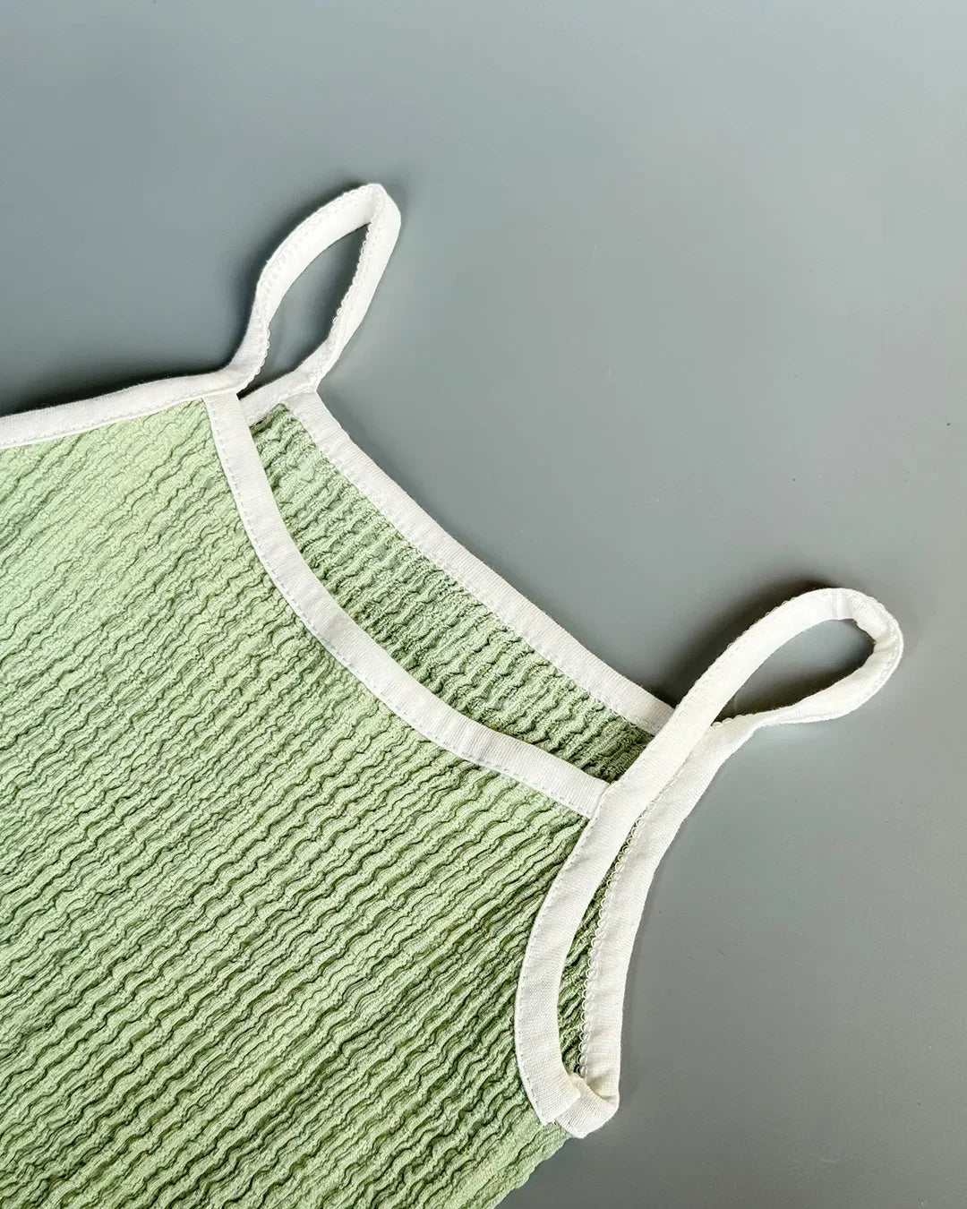 Green textured pot holder with white handles on a gray background
