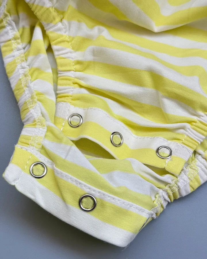 Yellow and white striped baby romper with button details on a gray background