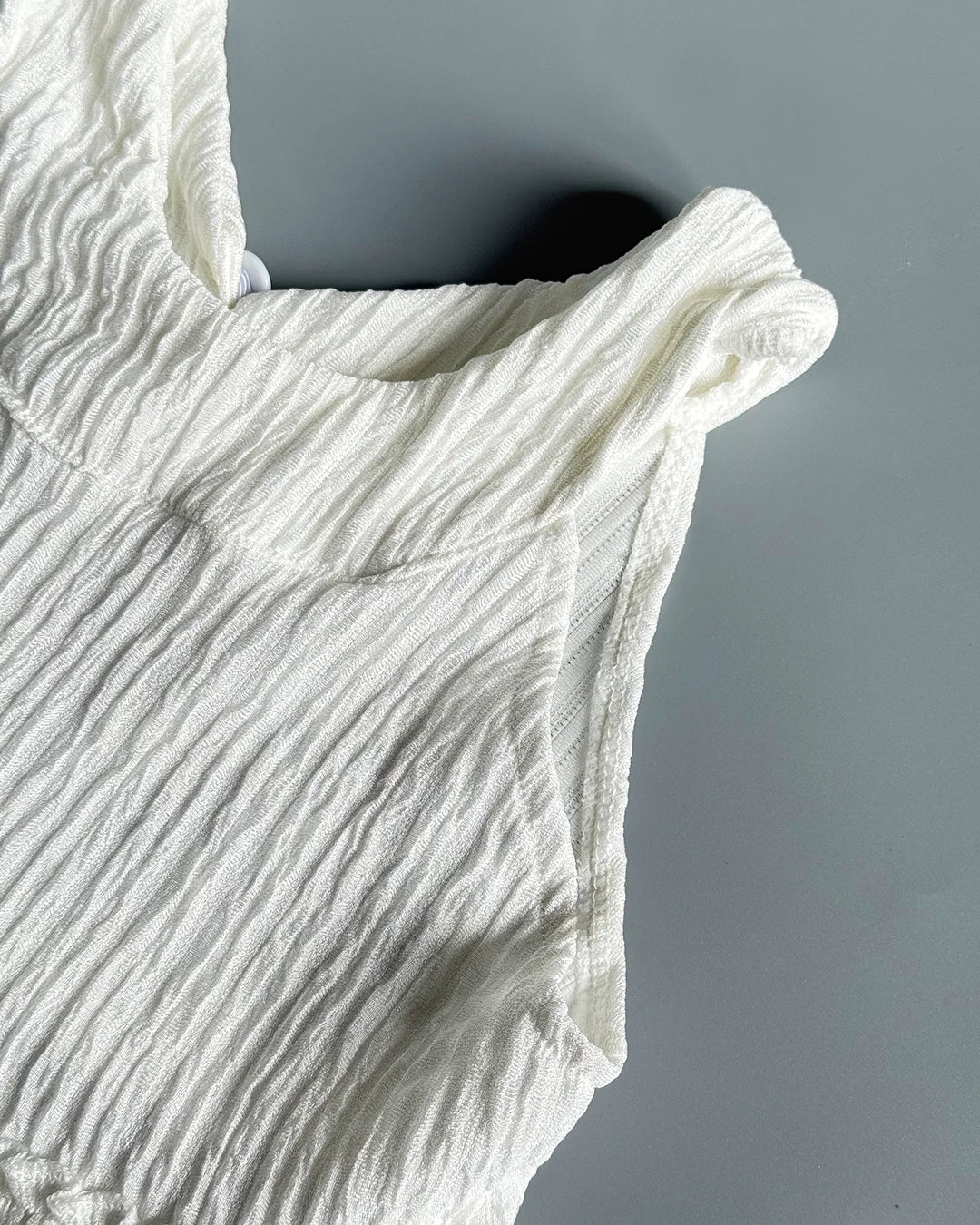 Close-up of a textured white garment against a gray background