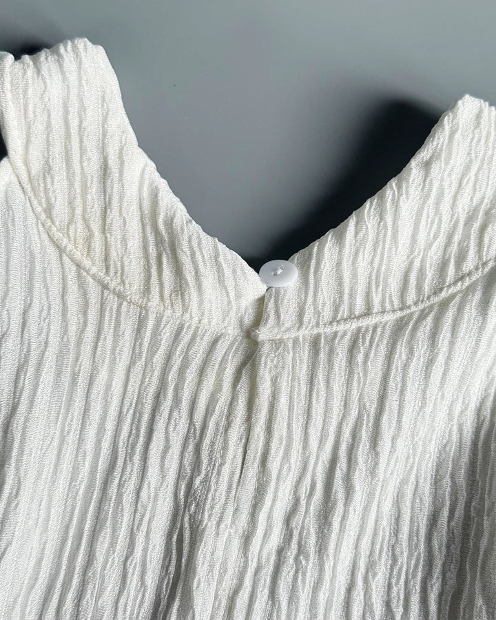 Close-up of a textured white garment with a button on a gray background