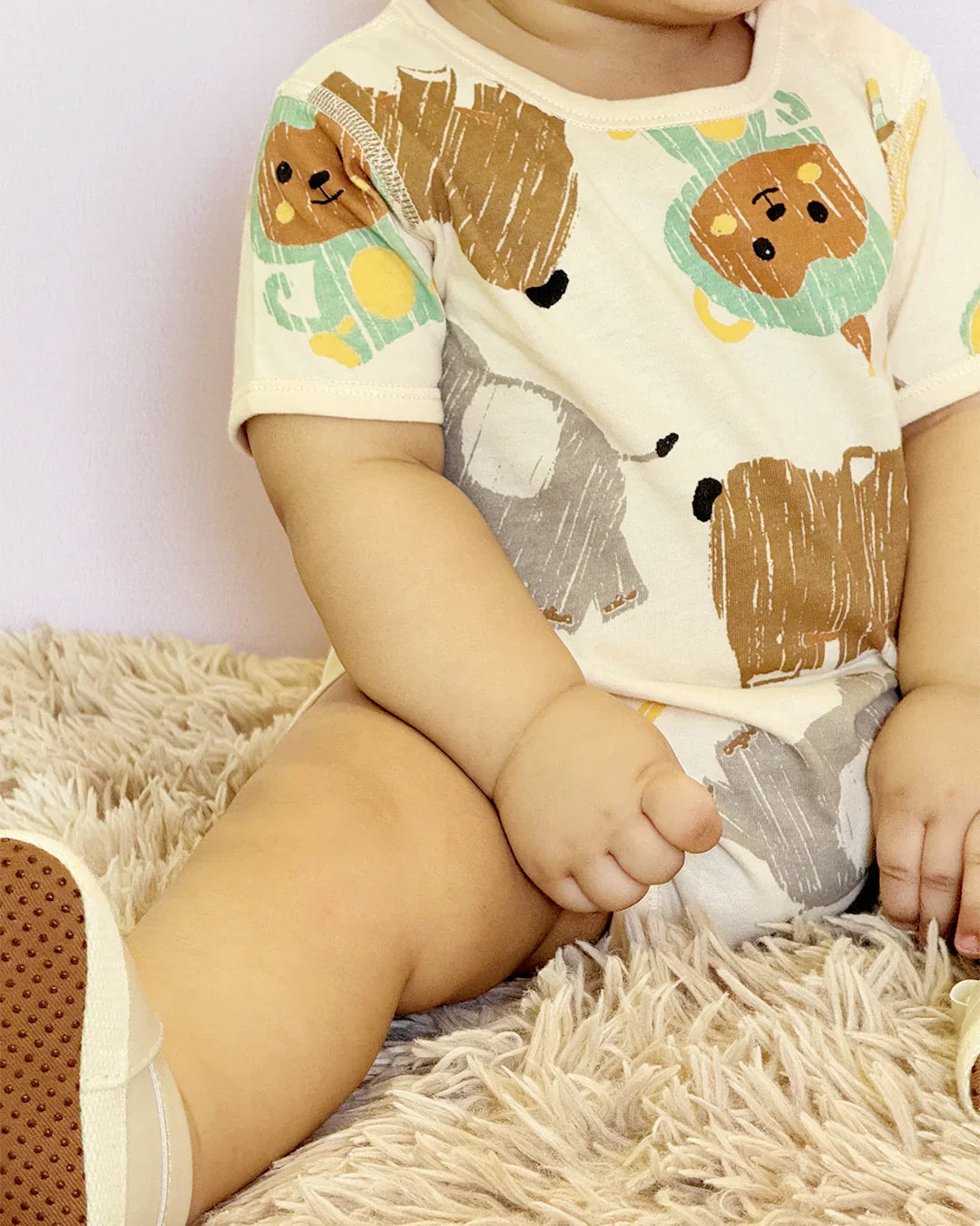 Child wearing a shirt with animal prints sitting on a textured surface.
