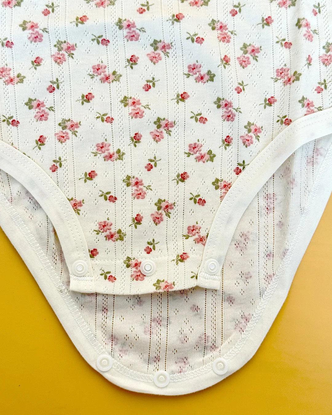 Floral-patterned baby bodysuit on a yellow background