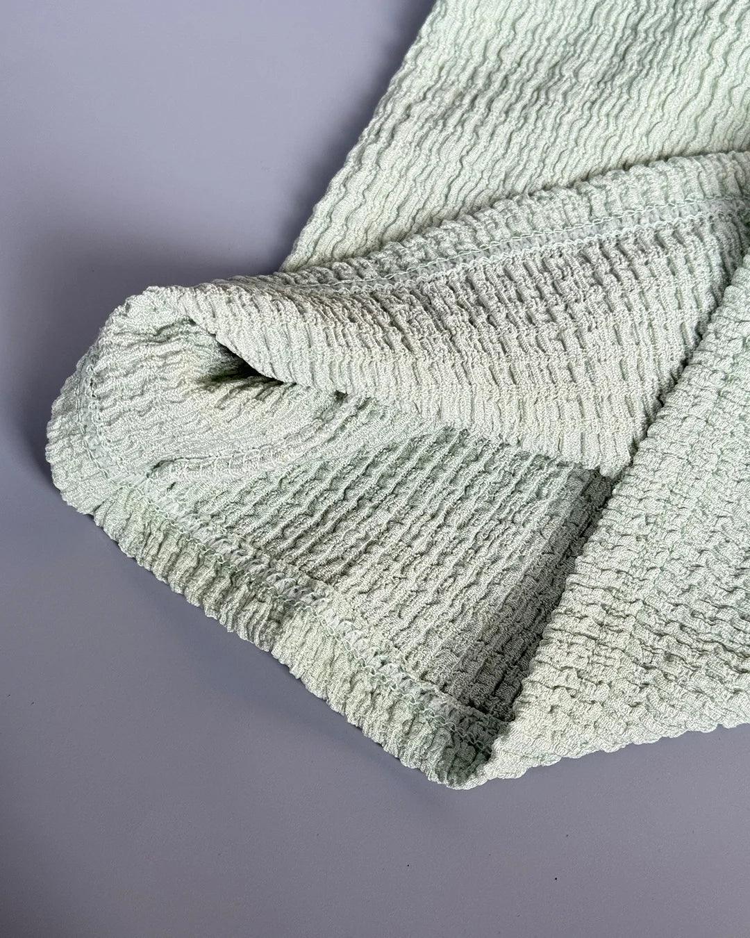 Textured green blanket on a gray background