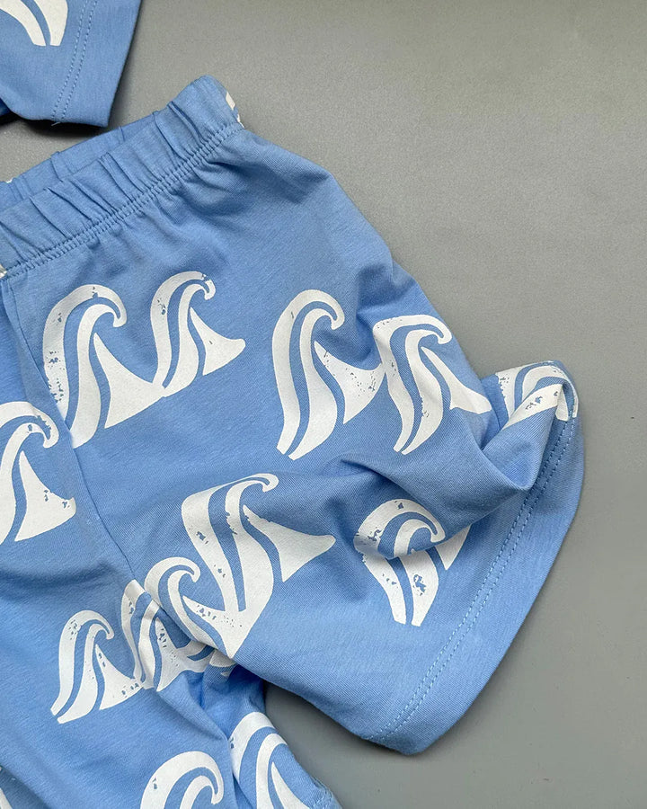 Blue shorts with white wave patterns on a gray surface