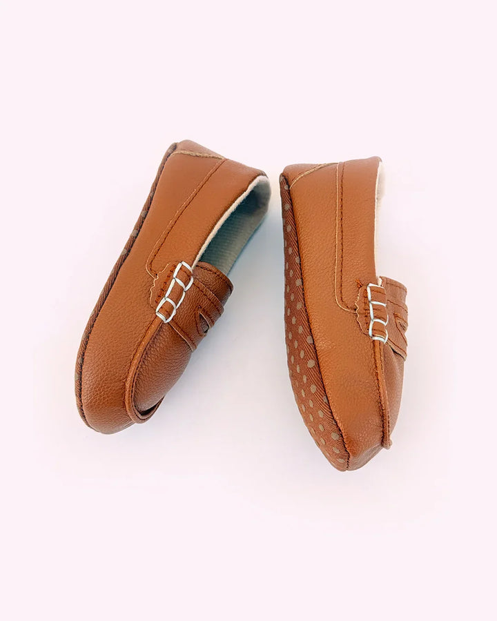 Pair of brown loafers with a silver buckle on a white background