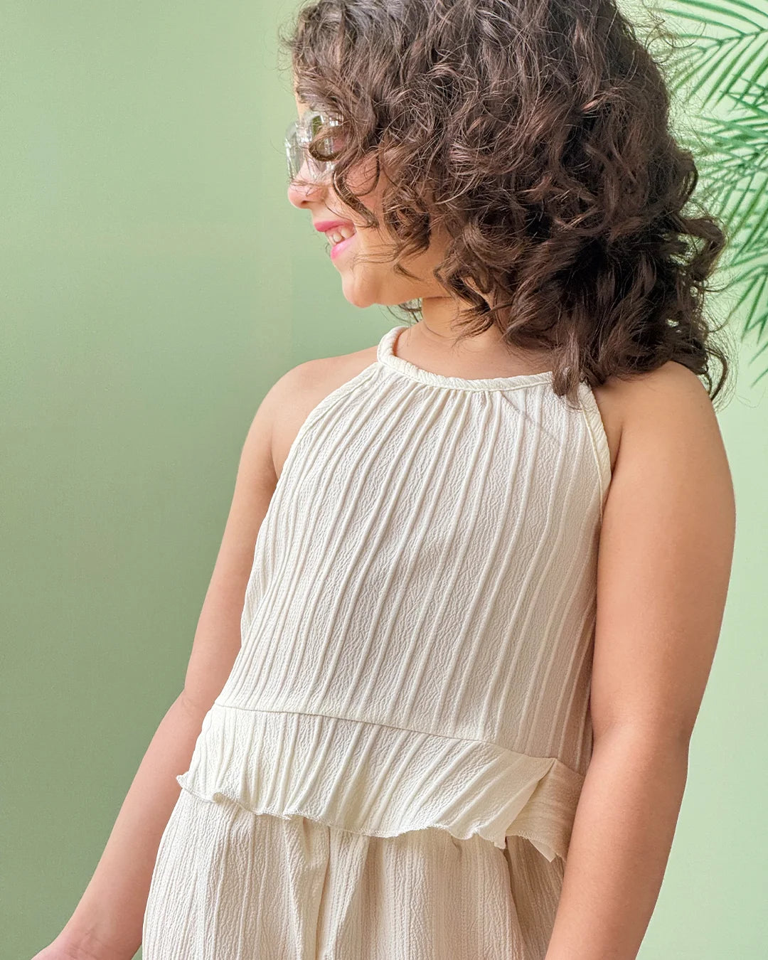 baby girl wearing a beige dress against a green background