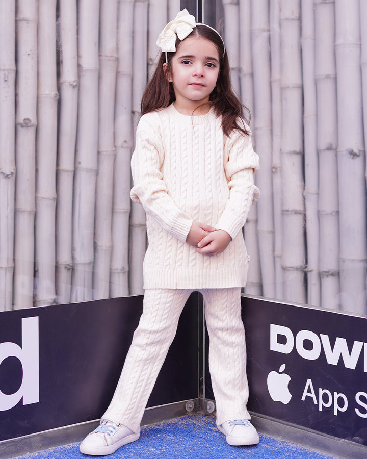 Young girl in a white outfit standing in front of a branded backdrop
