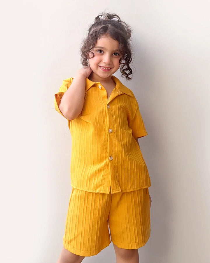 Child wearing a yellow outfit against a plain background