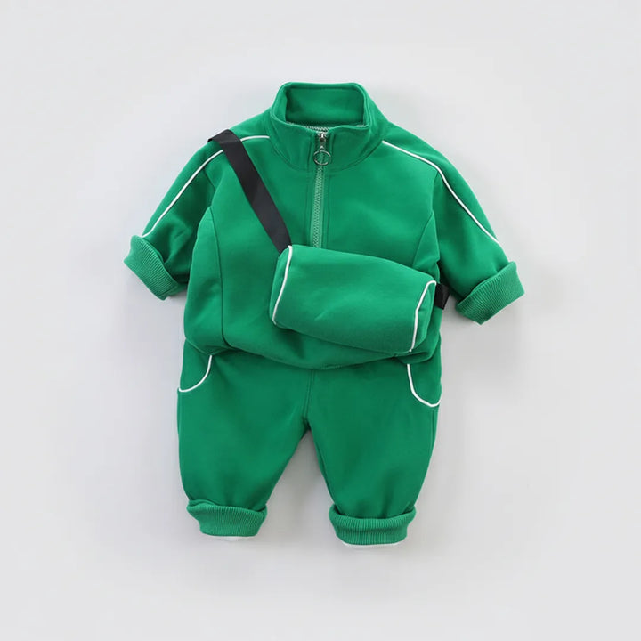Green children's tracksuit with a black strap on a light gray background