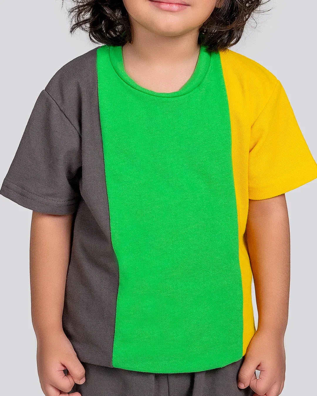 Child wearing a colorful shirt with gray, green, and yellow sections on a plain background