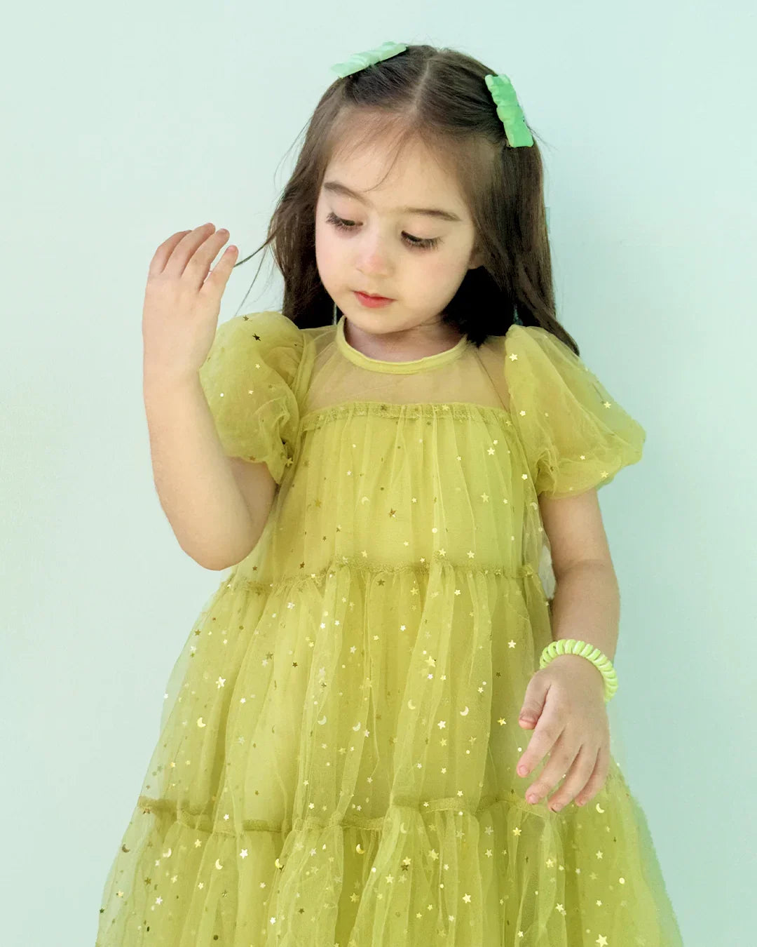 Young girl wearing a yellow dress with a light green background