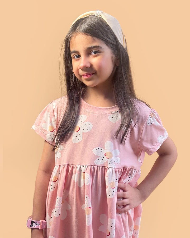 Young girl wearing a pink dress with floral patterns on a beige background