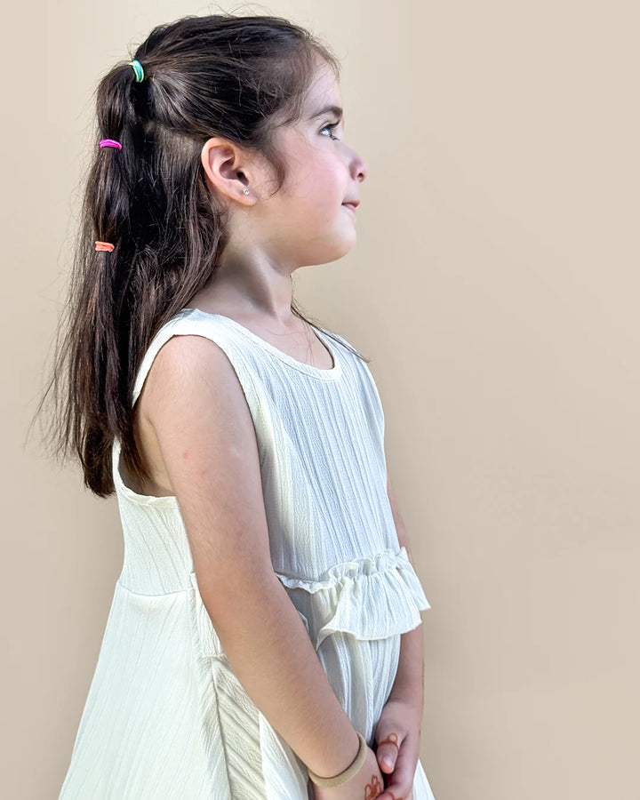 Young girl wearing a white dress against a beige background